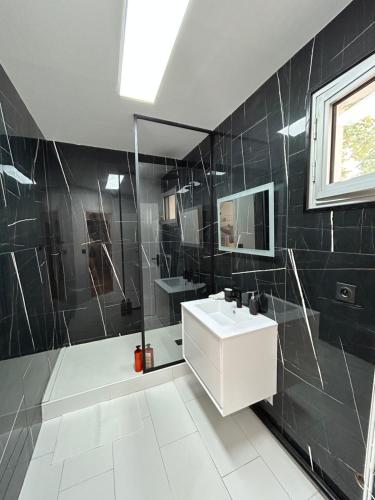 a bathroom with a white sink and black tiles at Superbe appartement au porte de Paris et du salon des expositions in Vanves