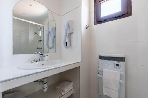 uma casa de banho branca com um lavatório e um espelho em Aec Village Vacances - Les Cèdres em Grasse