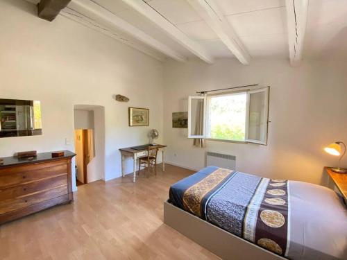 een slaapkamer met een bed, een bureau en een raam bij 06AW - Mas en pierre provençal rénové au calme in Le Rouret