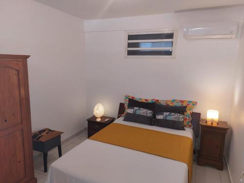 um quarto com uma cama com duas mesas de cabeceira e uma janela em Balaou em Les Anses-dʼArlets