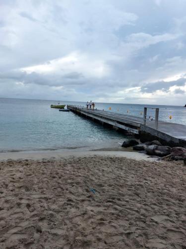 a pier in the ocean with people walking on it at Balaou in Les Anses-dʼArlets