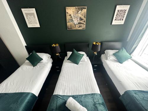 2 camas en una habitación con verde y blanco en The Valley Inn Liverpool, en Liverpool