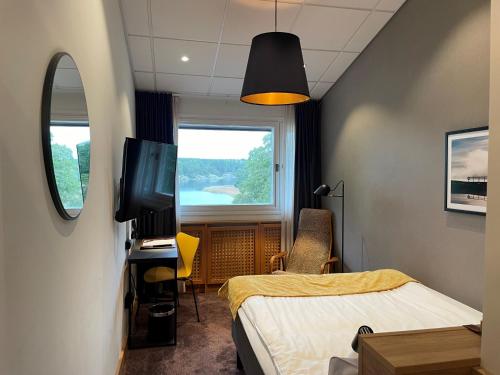 Habitación con cama, TV y ventana. en Skåvsjöholm Hotell och Möten, en Åkersberga