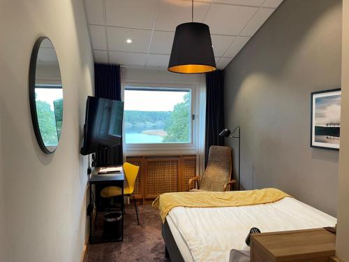 een kamer met een bed, een tv en een raam bij Skåvsjöholm Hotell och Möten in Åkersberga