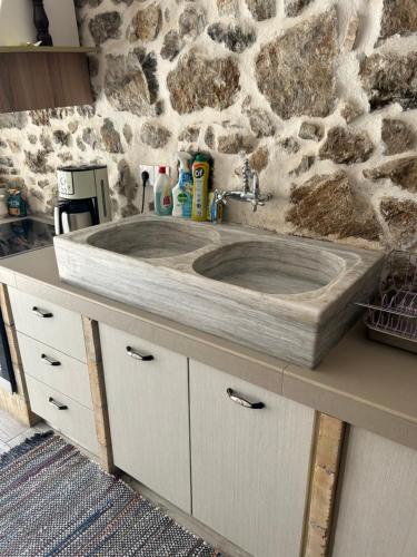 W łazience znajduje się drewniana umywalka z kamienną ścianą. w obiekcie Tulip House w mieście Yerakárion