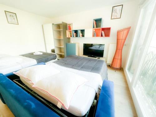two beds in a room with a tv and a room with at Kim -TiAM CONCIERGERIE - Standing - VILLIERS SUR MARNE - Paris Disney-Parking Gratuit in Villiers-sur-Marne