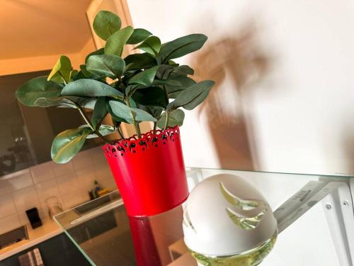 ヴィリエ・シュル・マルヌにあるKim -TiAM CONCIERGERIE - Standing - VILLIERS SUR MARNE - Paris Disney-Parking Gratuitのガラス台の上に植物を置いた赤花瓶