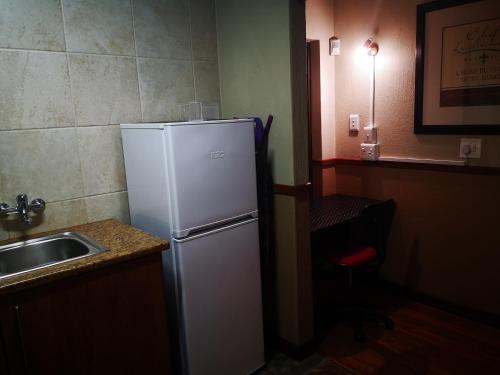a kitchen with a white refrigerator next to a sink at De Oude Herberg in Centurion