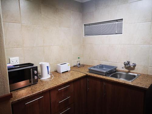 a kitchen counter with a microwave and a sink at De Oude Herberg in Centurion
