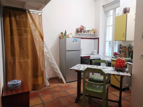 a kitchen with a table and a refrigerator at Charmant studio atypique in Paris