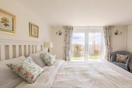 1 dormitorio con cama blanca y ventana en Oak Tree Cottage, en Uckfield