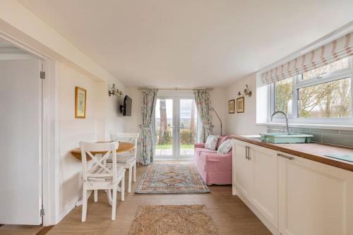 cocina con fregadero y mesa con silla en Oak Tree Cottage, en Uckfield