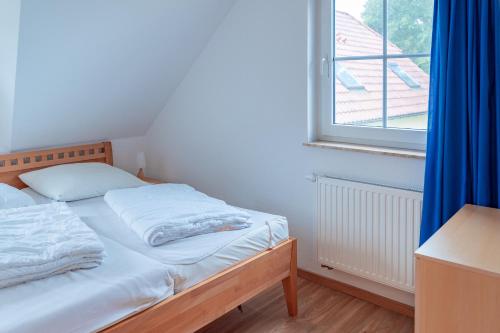 a bedroom with a bed with a blue curtain and a window at Am Deich 40 in Zingst