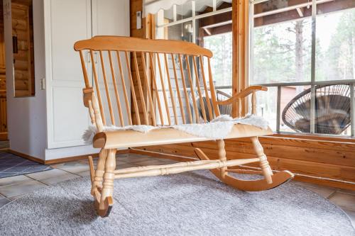 a wooden rocking chair sitting in a room with a window at Pyhä Nallentupa in Pyhätunturi
