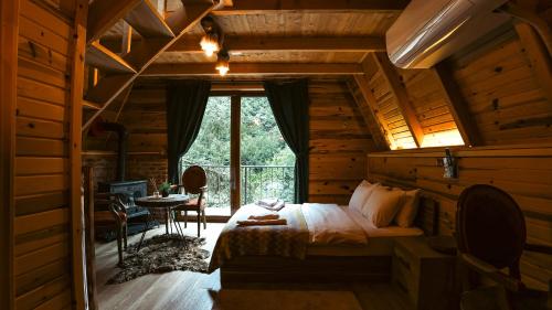 a bedroom in a log cabin with a bed and a window at bungalove tatil köyü in Çamlıhemşin