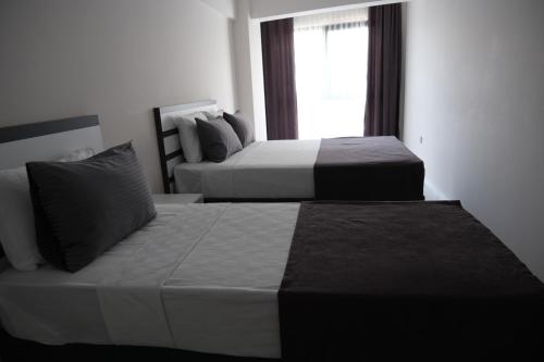 two beds in a hotel room with a window at JK Business in Denizli
