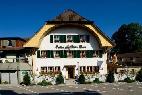 un gran edificio blanco con ventanas con contraventanas verdes en Gasthof zum Wilden Mann, en Aarwangen