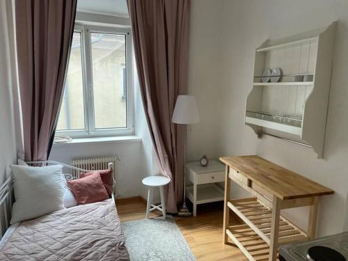 Habitación pequeña con cama, escritorio y ventana. en Graz City Centre Apartment, en Graz