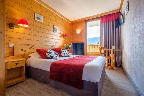 une chambre avec un lit dans une pièce aux murs en bois dans l'établissement AEC Vacances - Forgeassoud, à Saint-Jean-de-Sixt