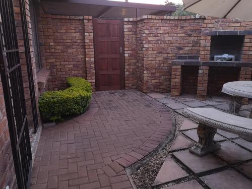 a brick patio with a brick fireplace and a red door at De Oude Herberg in Centurion
