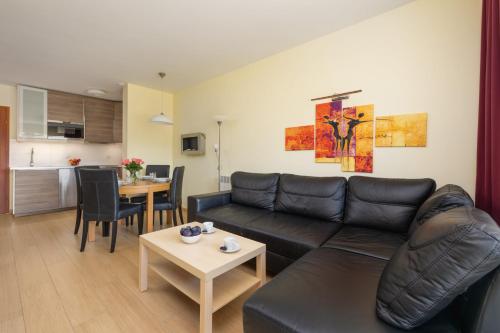 a living room with a black leather couch and a table at Spacerowa Modern Apartment by Renters in Łukęcin