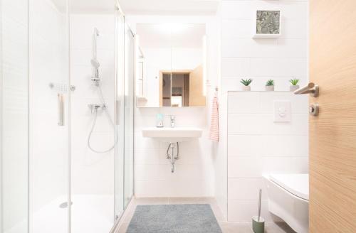 biała łazienka z prysznicem i umywalką w obiekcie Panoráma Sétány Apartman Fonyód w mieście Fonyód