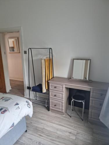 een slaapkamer met een dressoir met een spiegel en een bed bij Lido Bay Ground Floor Apartment in Largs