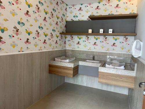 a bathroom with a sink and a wallpaper with birds at São Pedro Thermas Resort in São Pedro