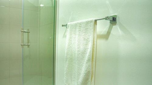 a shower with a white towel and a glass door at Premium space in Santiago- 5 Min Away from airport in Santiago de los Caballeros
