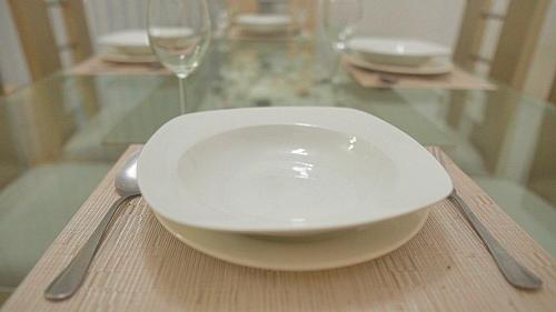 a bowl and a spoon on a table with a wine glass at Premium space in Santiago- 5 Min Away from airport in Santiago de los Caballeros