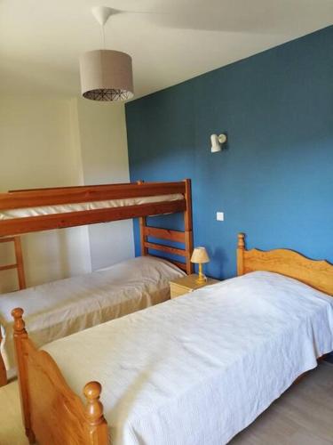 une chambre avec deux lits et un mur bleu dans l'établissement Maison au cœur du Sancy, à Férérolles