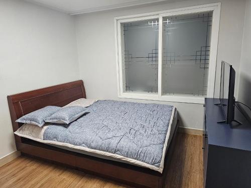 a bedroom with a bed and a window and a television at Byeongjeom-yeok Stay 