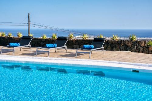 2 sillas sentadas junto a una piscina en Villa Luciano "Spirit of the Canaries" en Tías