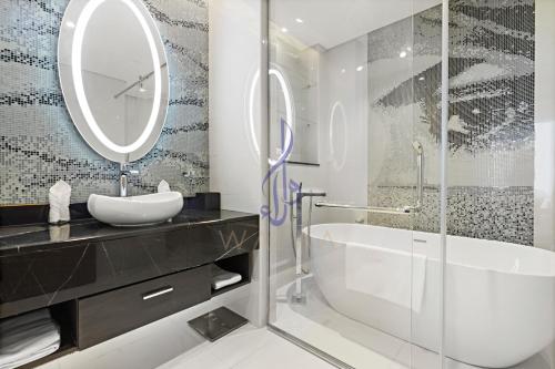 ein Badezimmer mit einer Badewanne, einem Waschbecken und einem Spiegel in der Unterkunft Walaa Homes Luxury 2BR at DAMAC Esclusiva Tower Riyadh-3104 in Riad