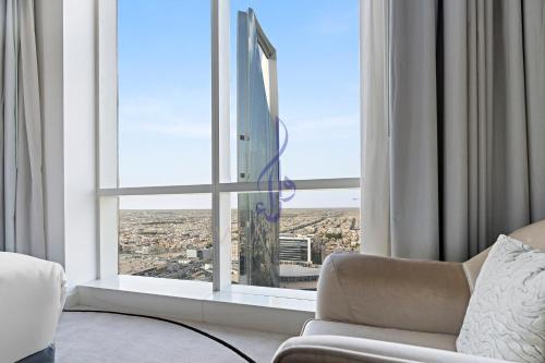 sala de estar con sofá y ventana grande en Walaa Homes Luxury 2BR at DAMAC Esclusiva Tower Riyadh-3104, en Riad