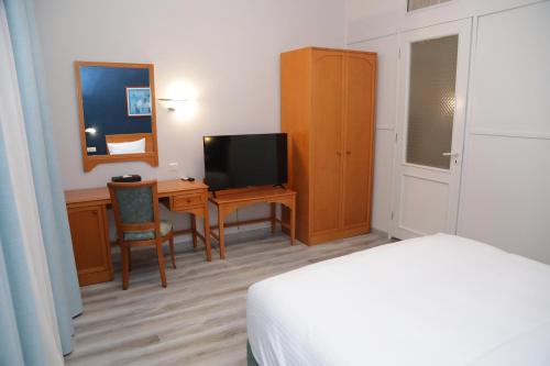 a bedroom with a bed and a desk with a television at El Sheikh Suites Hotel in Beirut