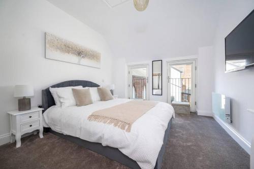 a white bedroom with a large bed and a tv at 3 King Charles Court, Sudbury in Sudbury