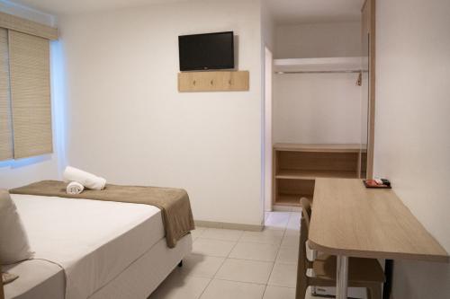 a bedroom with a bed and a table and a television at Pousada Areia do Forte in Cabo Frio