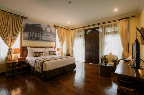 a bedroom with a bed and a desk and a television at Ombak Sunset in Gili Trawangan