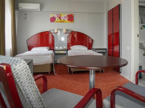 バンドゥルマにあるHOTEL EKENのベッド2台、テーブル、椅子が備わる客室です。