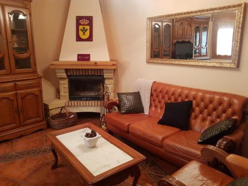 sala de estar con sofá de cuero y chimenea en Rincón de Ayllon, en Ayllón