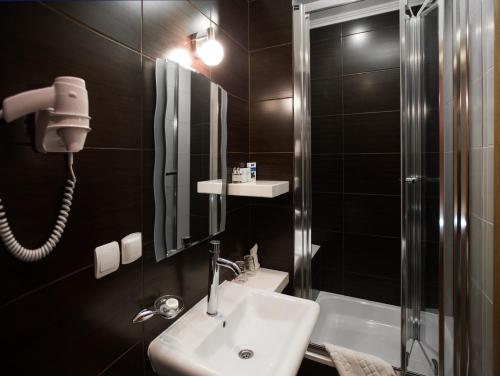 een badkamer met een wastafel, een douche en een spiegel bij Eney Budget in Lviv