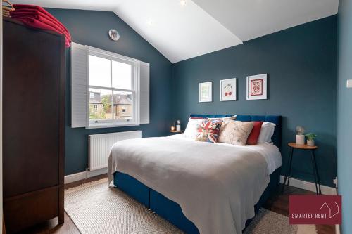 a blue bedroom with a bed and a window at Kingston upon Thames - 3 Bedroom House in Kingston upon Thames