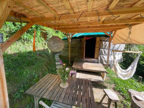 uma tenda com uma mesa de madeira e uma rede de descanso em Les songes du chêne em Augirein