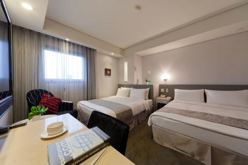 a hotel room with two beds and a desk at Harbor View Hotel in Keelung