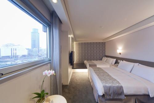 a hotel room with two beds and a large window at Harbor View Hotel in Keelung