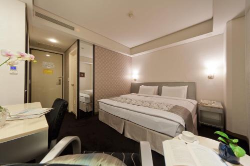 a hotel room with a bed and a table and chairs at Harbor View Hotel in Keelung