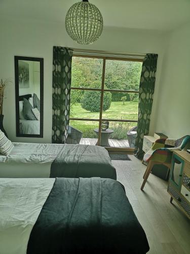 une chambre avec deux lits et une grande fenêtre dans l'établissement LA PAUSE, à Surville