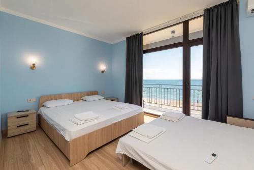 two beds in a room with a view of the ocean at Вилла Лагуна in Lidzava