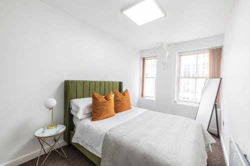 ein weißes Schlafzimmer mit einem Bett mit orangefarbenen Kissen in der Unterkunft The Olive Green Loft in Leicester